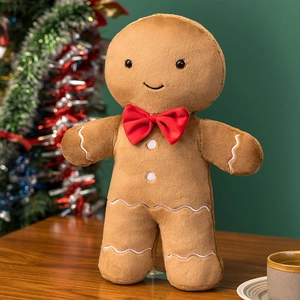 Close-up of soft gingerbread man plush pillow with festive red bow and white embroidery