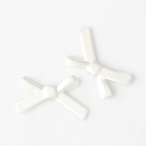 Detailed macro view of two white alloy bow-shaped beads for DIY jewelry making