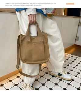 Close-up of khaki canvas shoulder bag with dual front pockets and adjustable strap