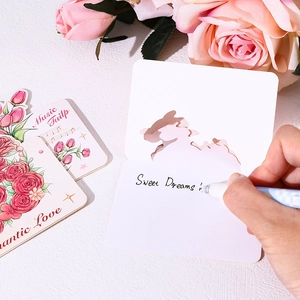Close-up of a hand writing sweet dreams on a hollow floral greeting card with roses