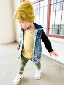 Toddler wearing a yellow knitted beanie with smiley patch and casual denim vest outfit