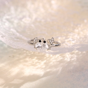 Macro shot of silver crab ring with sparkling zircon stone on wavy blue background