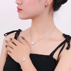 Detailed view of silver heart shell pearl necklace, bracelet and earrings set on model