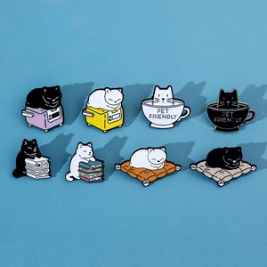 Flat lay of 8 assorted cartoon cat metal enamel pins on a blue background