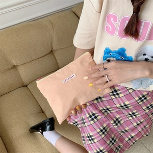 Detail of peach pink makeup pouch with zipper and SOZANKA logo held by a hand