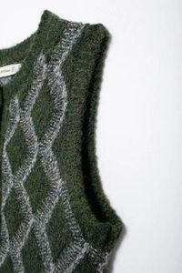 Gros plan sur la texture du motif en losange et l'étiquette d'un gilet en laine