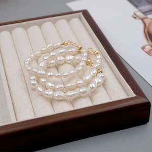 Elegant multilayer baroque freshwater pearl bracelet with gold hardware on a wooden tray