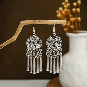 Detailed shot of retro antique silver bohemian earrings with metal fringe on wood