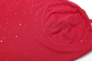 Detailaufnahme des roten Netzstoffs mit funkelnden Glitzerakzenten auf diesem Kleid