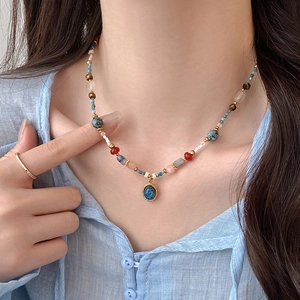 Détail d'un collier de perles ethnique avec pendentif en pierre bleue sur lin