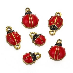 Macro shot of red and black enamel ladybug charms with gold metal edges for DIY jewelry