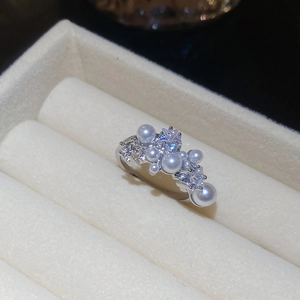 Macro shot of silver pearl and zircon cluster ring tucked into a beige jewelry box