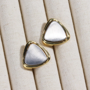 Detail of geometric triangle earrings with gold frame and brushed silver finish