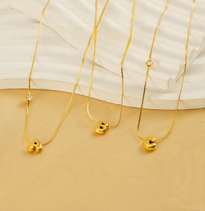 Detailed macro view of gold-plated stainless steel initial pendants with small zircons
