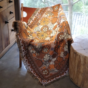 Retro floral woven throw blanket with orange tassels on leather chair for home decor