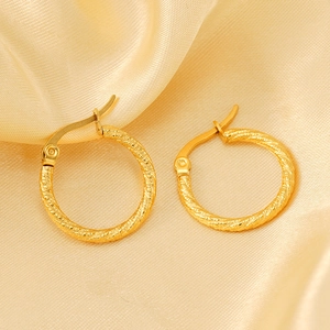 Classic golden twisted hoop earrings with spiral texture on elegant silk background