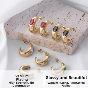Detailed macro of C-shaped gold stainless steel earrings with oval colored zirconia gems