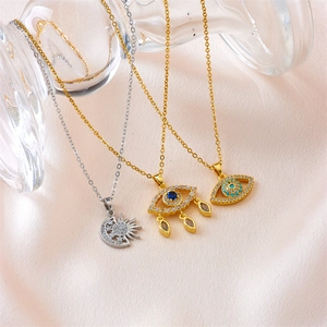 Three elegant evil eye and sun-moon necklaces on pink silk background with crystal accents