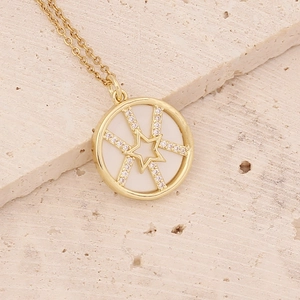 Close-up of a gold necklace with a white circular pendant and a zircon star inlay