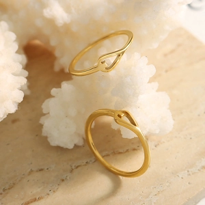 Minimalist gold knotted stainless steel rings displayed on elegant white coral decor