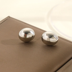 Macro detail of polished silver ball stud earrings with high mirror finish on leather surface