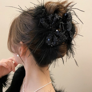 Detail of a black feather hair claw with sequins worn on hair for a stylish look