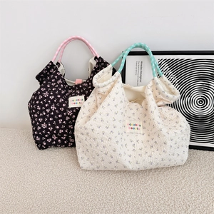 Detail view of quilted floral tote bags with woven rope handles and textured fabric