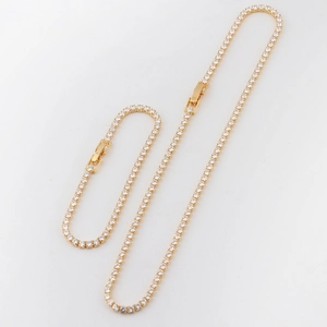 Detailed view of a gold tennis necklace and bracelet set with cubic zirconia stones