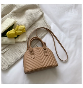 Detail of khaki shell bag with V-shaped quilting, tulip decor on white fabric