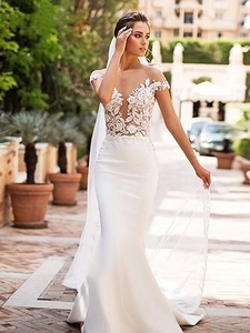 Detailed embroidery on white mermaid wedding dress with sheer mesh neckline and long train