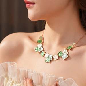 Détail d'un collier doré avec des pendentifs carrés en émail vert et bleu sur mannequin