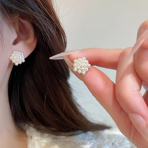 Detailed view of floral pearl stud earrings with gold base worn on the ear
