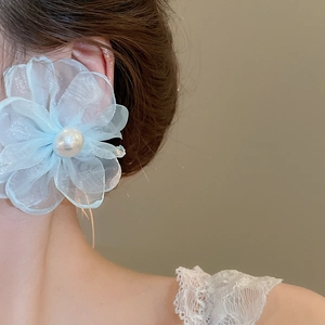 Macro detail of light blue chiffon flower earring featuring a central white pearl