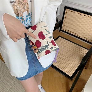Macro shot of floral pattern makeup bag with purple woven tassel zipper detail
