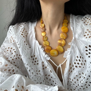 Detail of yellow gradient shell beads with iridescent luster on a bohemian necklace