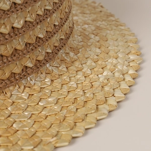 Détail macro du chapeau de plage en paille tressée avec rayures brunes et bord dentelé