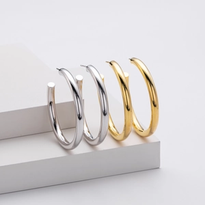 Macro shot of minimalist gold and silver thick C-shaped hoop earrings on white display