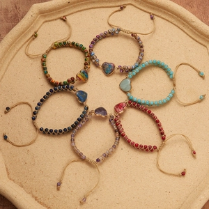 Macro view of handmade layered stone bracelets with heart charm on stone tray