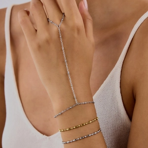 Detailed view of elegant silver hand chain bracelet with ring worn by model
