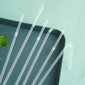 Individually wrapped disposable flexible plastic straws on a green tray with mint leaf