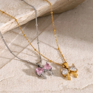 Detailed macro shot of 18k gold and silver bow necklaces with heart zirconia on stone
