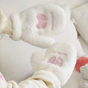 Detail of plush white mittens with pink bow embroidery and cozy ribbed cuffs