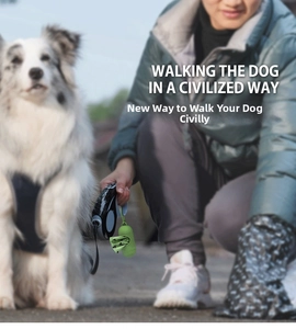 Portable green capsule waste bag dispenser with hook attached to a pet leash outdoors