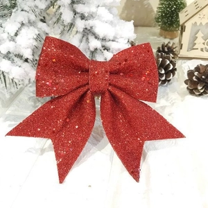 Sparkling red glitter Christmas bow ornament on tree branch for festive holiday decor