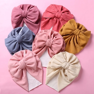 Detail view of colorful soft faux cashmere baby turban hats with large elegant bows