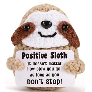 Macro shot of handmade crochet sloth holding a card with positive inspirational quote