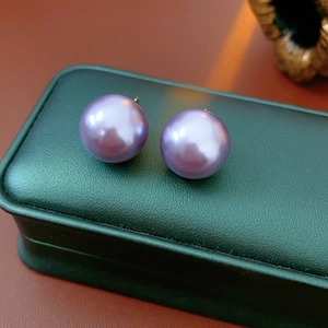 Detail of elegant purple pearl stud earrings placed on a vintage green jewelry box