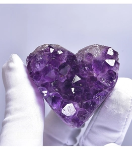 Macro shot of a heart-shaped purple amethyst cluster held by a gloved hand