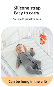Orange fox sleep soother with silicone strap hung on a crib beside a sleeping baby