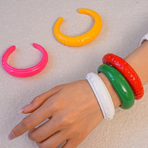 Dettaglio ravvicinato di bracciali in resina colorata con finitura lucida effetto rughe